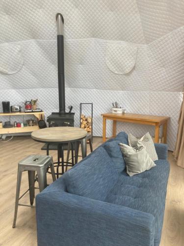a living room with a blue couch and a table at Open Sky Glamping Kawartha Dome in Marmora