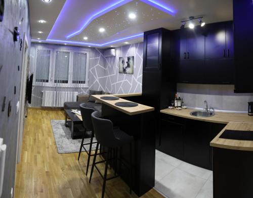 une cuisine avec des placards violets et un bar avec des tabourets dans l'établissement MYSTIC, à Subotica