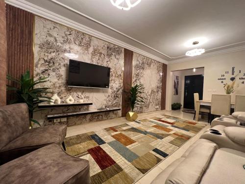 a living room with a couch and a tv on a wall at Luxurious VIP apartment in Madinaty furnished with high end hotel furniture in Madinaty