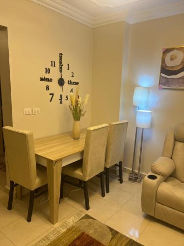 a dining room table with chairs and a clock on the wall at Luxurious VIP Apartment in Madinaty Furnished with High End Hotel Furniture in Madinaty