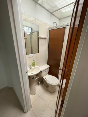 ein Badezimmer mit einem WC, einem Waschbecken und einem Spiegel in der Unterkunft Casa Medellin in Medellín
