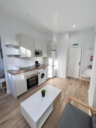 a kitchen with white cabinets and a white table at Lofts IFEMA in Madrid