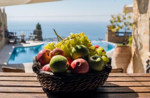 a basket of fruit on a table near a pool at Four Seasons Stonework Castle in Lagonissi