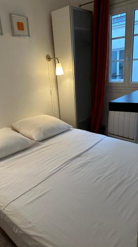 une chambre avec un lit blanc et une fenêtre dans l'établissement Haut-Marais Joli appartement., à Paris