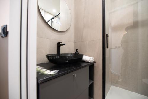 une salle de bain avec un lavabo noir et un miroir dans l'établissement Cosy home - Moulin rouge, à Paris