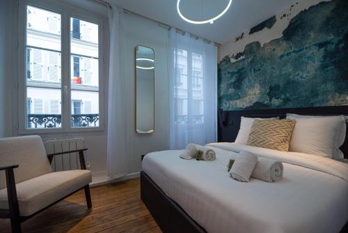 une chambre avec un grand lit et une chaise dans l'établissement Cosy home - Moulin rouge, à Paris