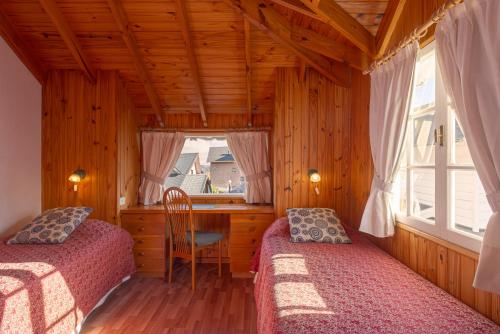 1 dormitorio con 2 camas, escritorio y ventana en Sol y Nieve en San Martín de los Andes