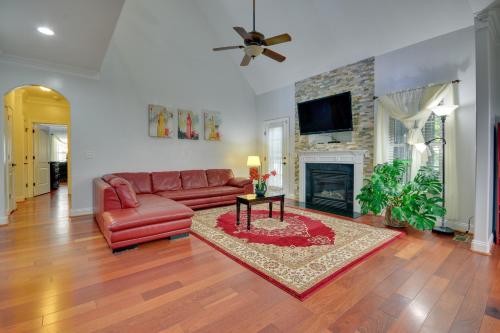 a living room with a red leather couch and a fireplace at High Point Vacation Rental with Private Deck! in High Point