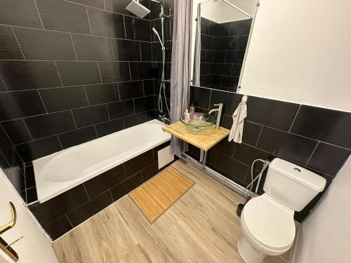 a bathroom with a white toilet and a bath tub at Suite Chic Lovhotêl in Persan