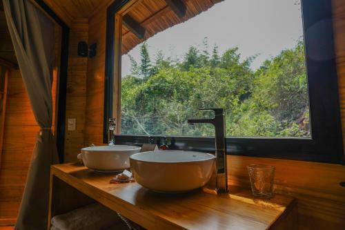 a bathroom with two sinks on a wooden counter with a window at Reserva Natural Iguazú - Pristine Luxury Camp in Puerto Libertad