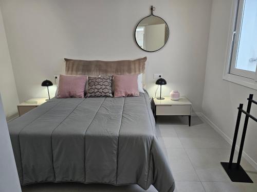 a bedroom with a bed with pink pillows and a mirror at Casa Pajo - Moderna, personal y con bicicletas in San Pedro del Pinatar