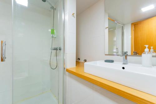 La salle de bains blanche est pourvue d'un lavabo et d'une douche. dans l'établissement Casa do Loureiro 1 - Seia - Serra da Estrela, à Seia