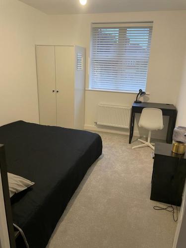 1 dormitorio con cama negra, escritorio y silla en Central 2-Bed Flat: Ideal for Nurses, Contractors, Relocators - Free WiFi & Parking, en Peterborough