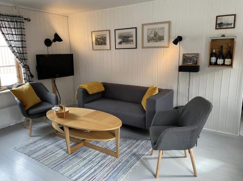 a living room with a couch and two chairs and a table at Charming Rorbu Stamsund Lofoten in Stamsund