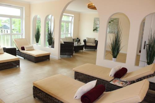 a living room with couches and chairs and mirrors at Hotel Flora in Fredersdorf