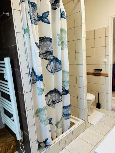 a shower curtain in a bathroom with a toilet at Chambre d’hotes in Démouville