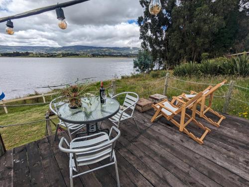 a table and chairs on a deck next to a lake at Glamping Yerbabuena in Toca