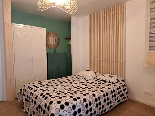 1 dormitorio con 1 cama con edredón blanco y negro en Le Bulotier en Granville