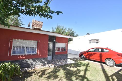 czerwony samochód zaparkowany przed czerwonym domem w obiekcie Kaiken Maison w mieście Villa Santa Cruz del Lago
