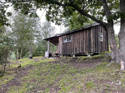 a wooden cabin on a hill with a tree at koselig liten hytte i Skien in Skien