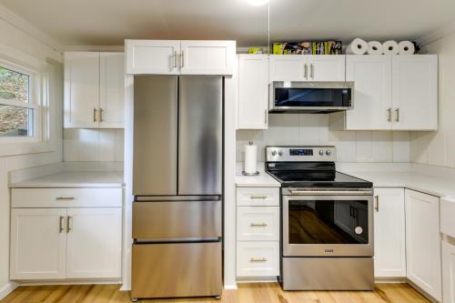 a kitchen with white cabinets and a stainless steel refrigerator at Horseshoe Lake Vacation Rental with Deck and Kayaks! in Batavia