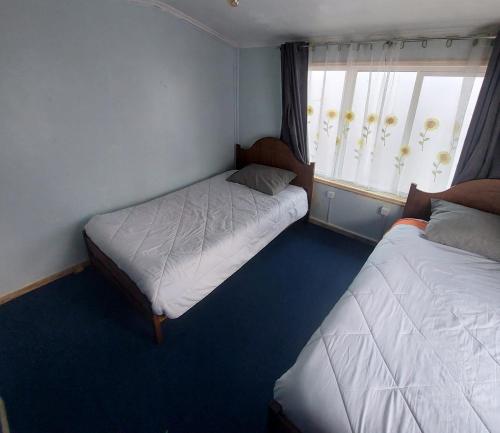 a bedroom with two beds and a window at Pies a tierra in Coihaique