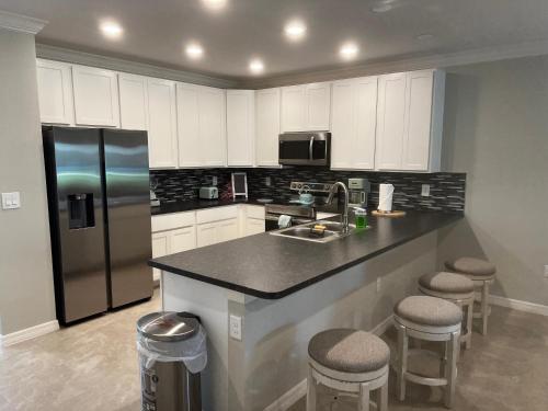 a kitchen with a sink and a refrigerator and stools at Luxurious Farm Style House in Kissimmee