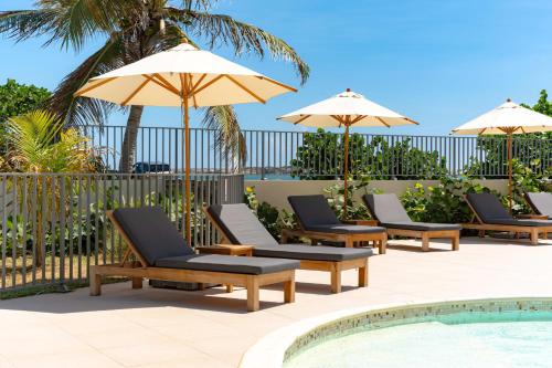 a group of chairs and umbrellas next to a pool at Spacious studio with pool and beach in Orient Bay in Orient Bay