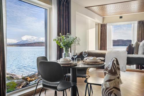 a living room with a table and chairs and a large window at Steam Pier Adventure Hotel in Kvaløya