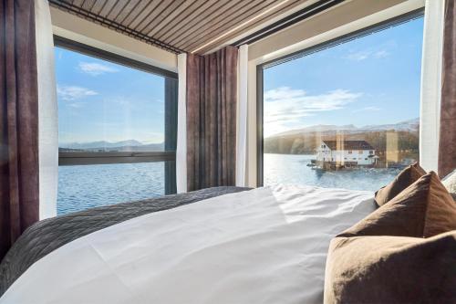 a bedroom with a large window overlooking the water at Steam Pier Adventure Hotel in Kvaløya