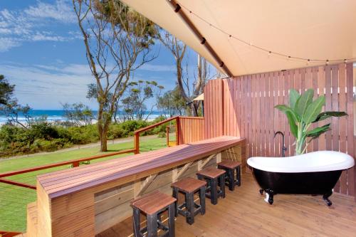 a bath tub sitting on a deck with stools at Ingenia Holidays Bonny Hills in Bonny Hills