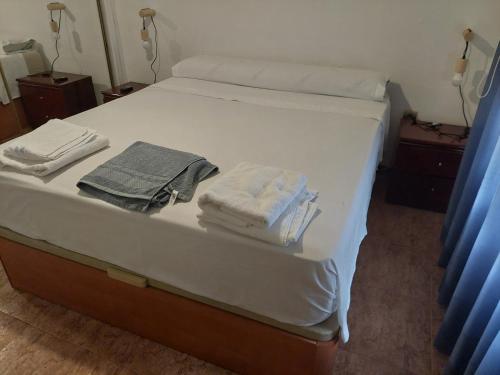 Una cama con sábanas blancas y toallas. en APARTAMENTO ESTACION a 3 min, en Córdoba