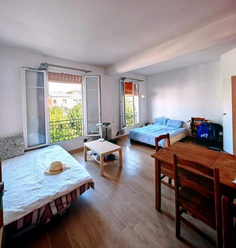 uma sala de estar com duas camas e uma mesa em Sean em Issy-les-Moulineaux