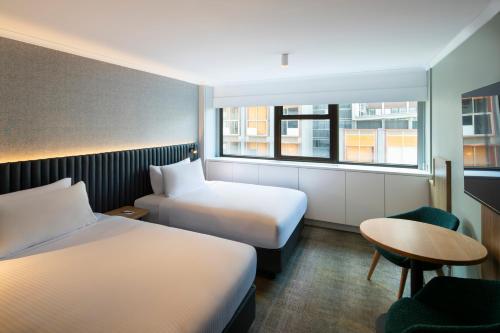 a hotel room with two beds and a table at Novotel Sydney City Centre in Sydney