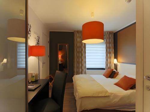 una camera d'albergo con letto, scrivania e lampade di Hotel Myrtilles a Vielsalm