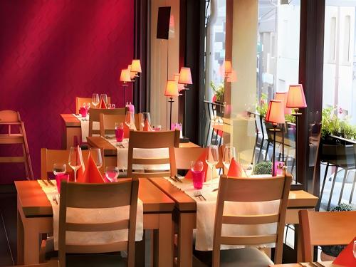 un restaurant avec des tables et des chaises en bois et des murs rouges dans l'établissement Hotel Myrtilles, à Vielsalm