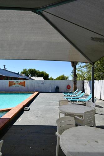a group of chairs and tables next to a swimming pool at Howard Johnson by Wyndham Near Schlitterbahn in New Braunfels
