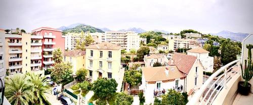 a city with buildings and palm trees and mountains at L’Exotique in Menton