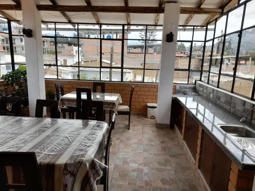 un restaurante vacío con mesas, sillas y ventanas en Casa Hospedaje"Los Capulies", en Carhuaz