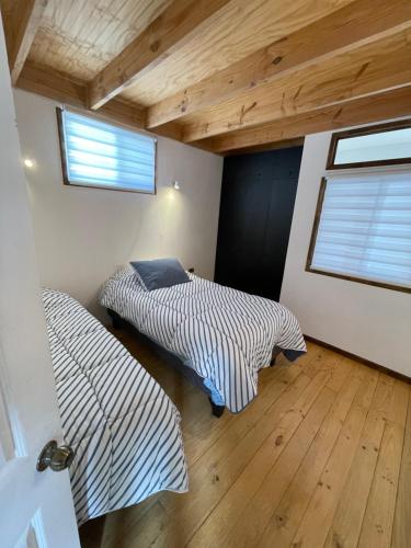 two beds in a room with wooden ceilings at Cabaña Maitencillo frente al mar in Maitencillo