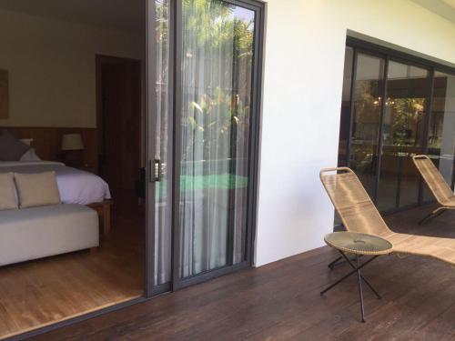 a room with sliding glass doors and a bed and a chair at The Kesari Luxury Villa in Sanur