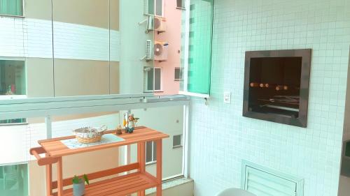 cocina con mesa y TV en la pared en Meia Praia Apartamento Perfeito, en Meia Praia