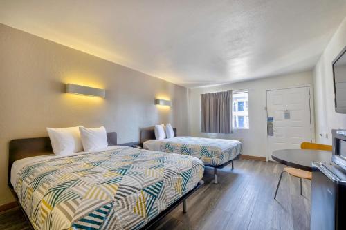 a hotel room with two beds and a table at Motel 6-Bryan, TX - College Station in Bryan
