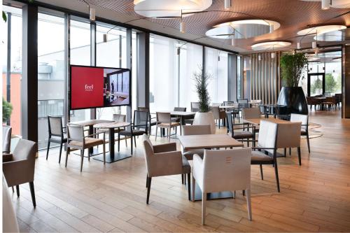 un ristorante con tavoli e sedie e uno schermo per proiezioni di NH Collection Olomouc Congress a Olomouc