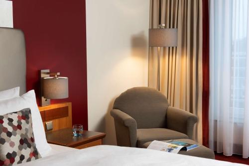 a hotel room with a chair and a bed at Dorint An den Westfalenhallen Dortmund in Dortmund