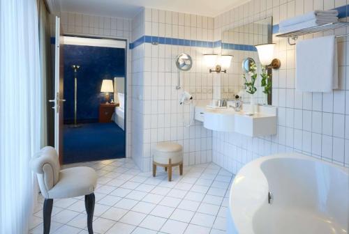 a white bathroom with a tub and a sink at Dorint An den Westfalenhallen Dortmund in Dortmund