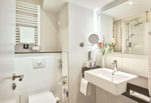 a white bathroom with a sink and a toilet at Dorint An den Westfalenhallen Dortmund in Dortmund