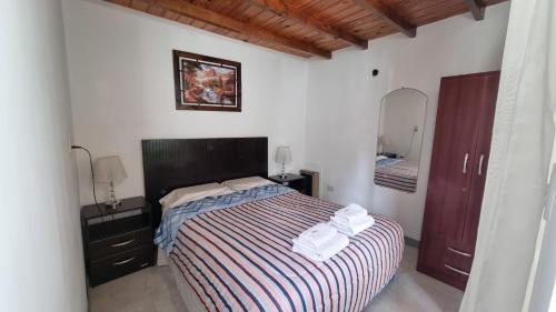 1 dormitorio con 1 cama con manta a rayas y espejo en Departamento Alejandra en Ushuaia