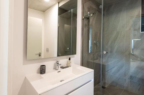 y baño blanco con lavabo y ducha. en Coral Point Executive studio Apartment, en Umdloti