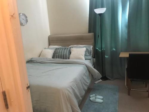 a bedroom with a bed and a desk and a lamp at Double Room close to Central London- Females Only in London